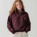 Vorderansicht eines weiblichen Models im bordeauxroten Half Zip mit Maus Relax-Stickerei.