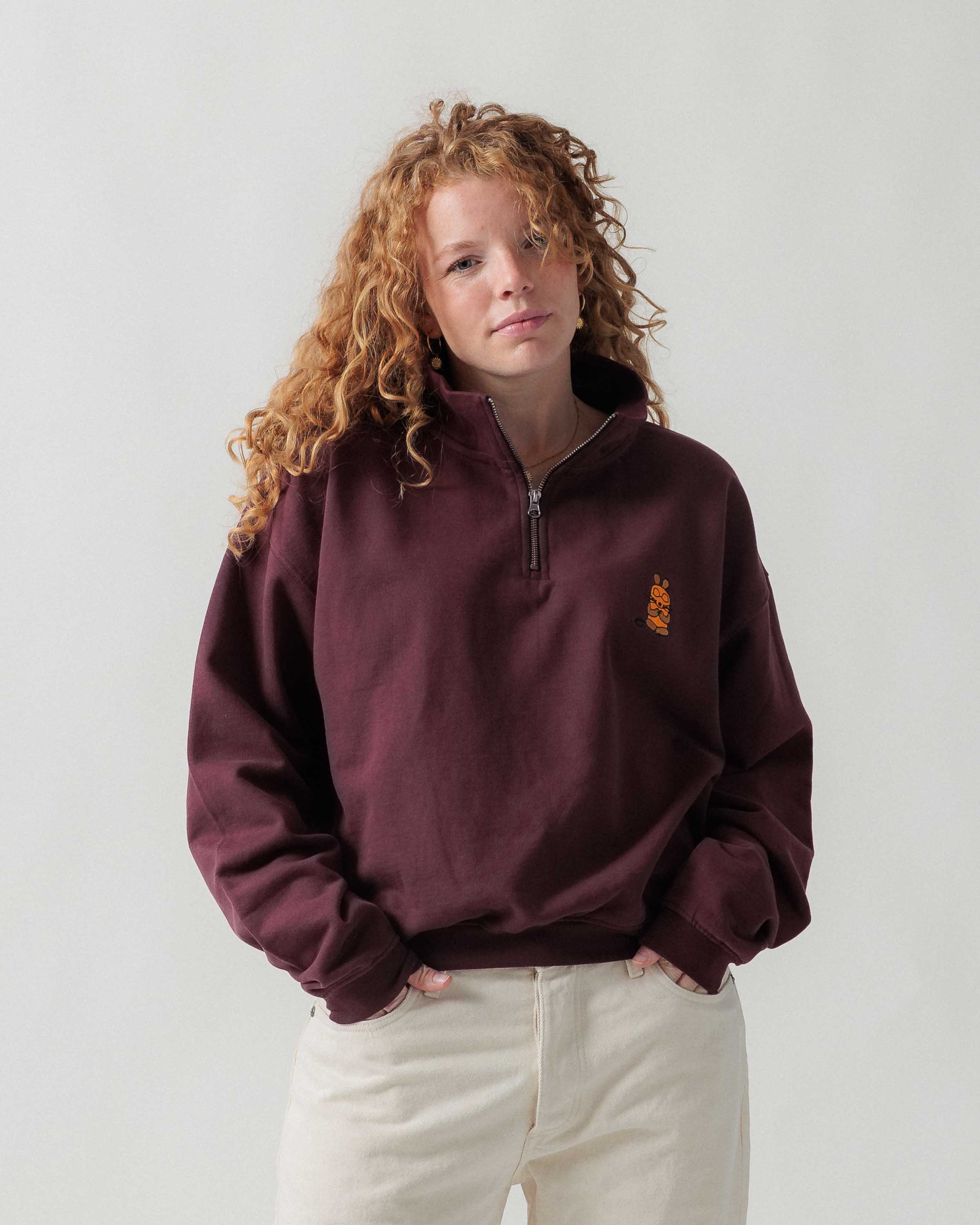 Vorderansicht eines weiblichen Models im bordeauxroten Half Zip mit Maus Relax-Stickerei.