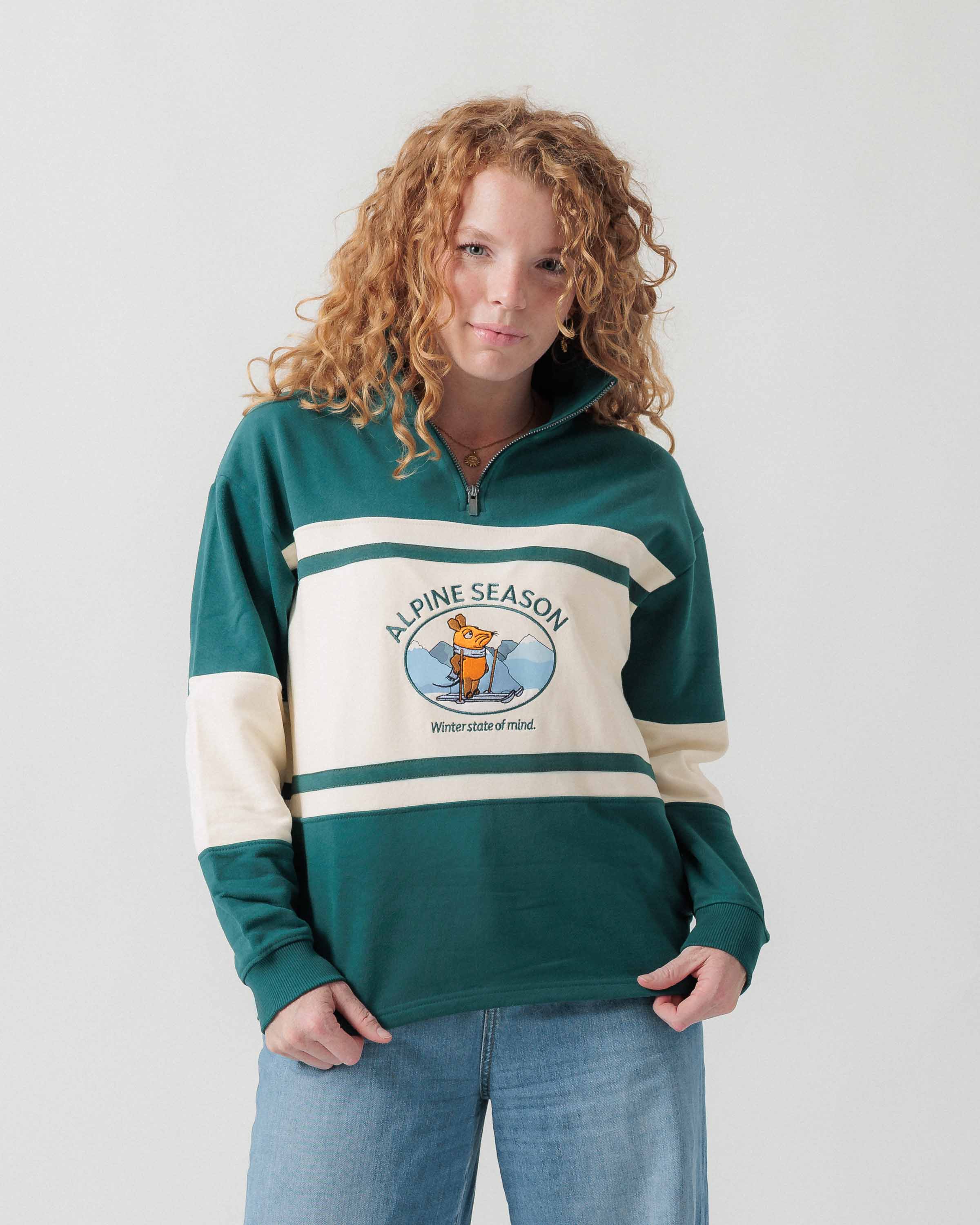 Vorderansicht eines weiblichen Models im grün-cremefarbenen Half Zip mit Maus Alpine-Motiv.