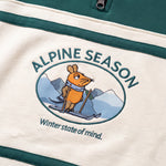 Detailaufnahme des Maus Alpine-Motivs auf dem grün-cremefarbenen Half Zip. Maus auf Skiern vor einer Bergkulisse.