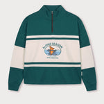 Vorderansicht des grün-cremefarbenen Half Zips mit Maus Alpine-Motiv. Maus auf Skiern vor einer Bergkulisse.