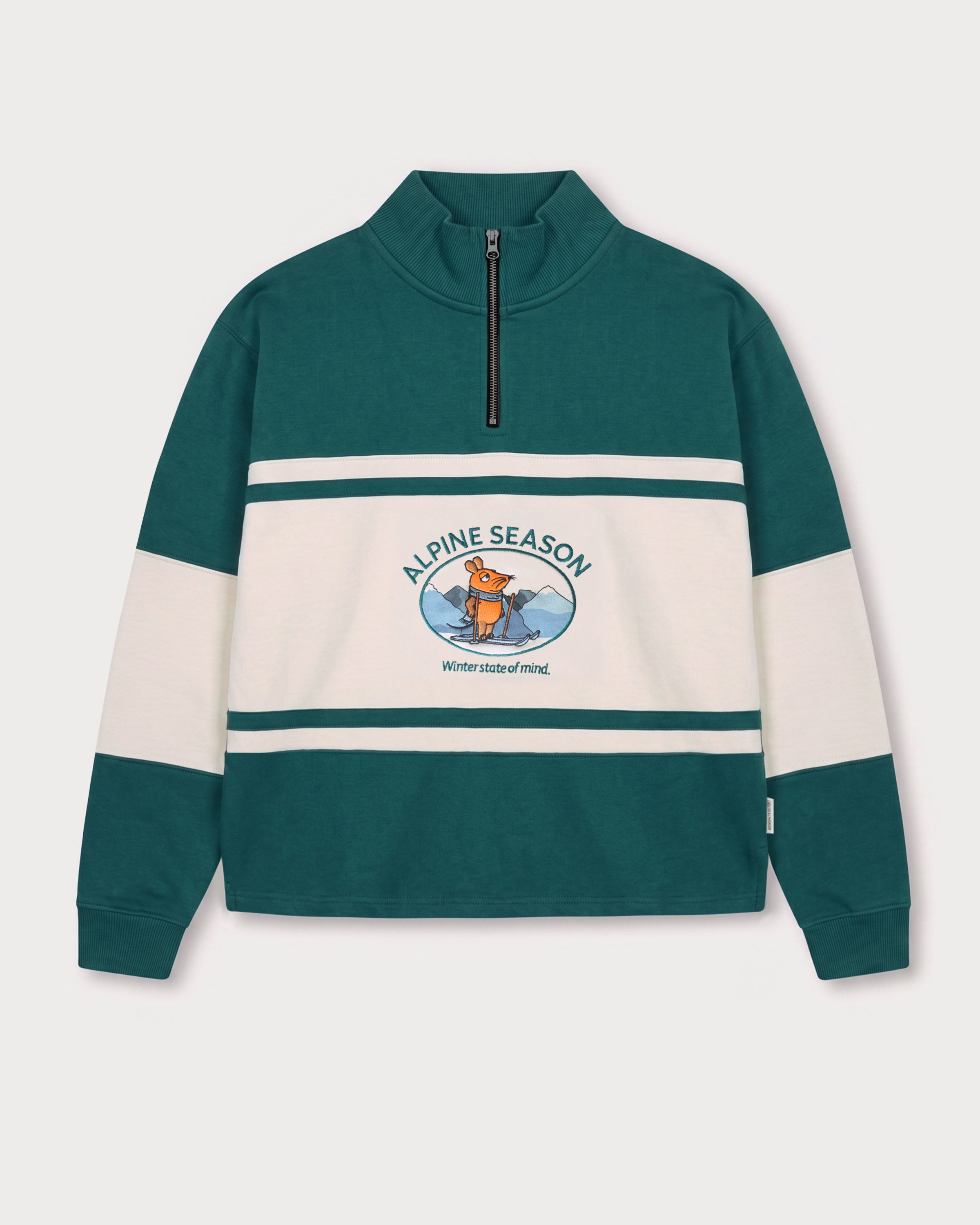 Vorderansicht des grün-cremefarbenen Half Zips mit Maus Alpine-Motiv. Maus auf Skiern vor einer Bergkulisse.