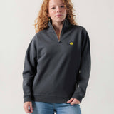 Vorderansicht eines weiblichen Models im grauen Half Zip mit einem fliegenden Tennisball.