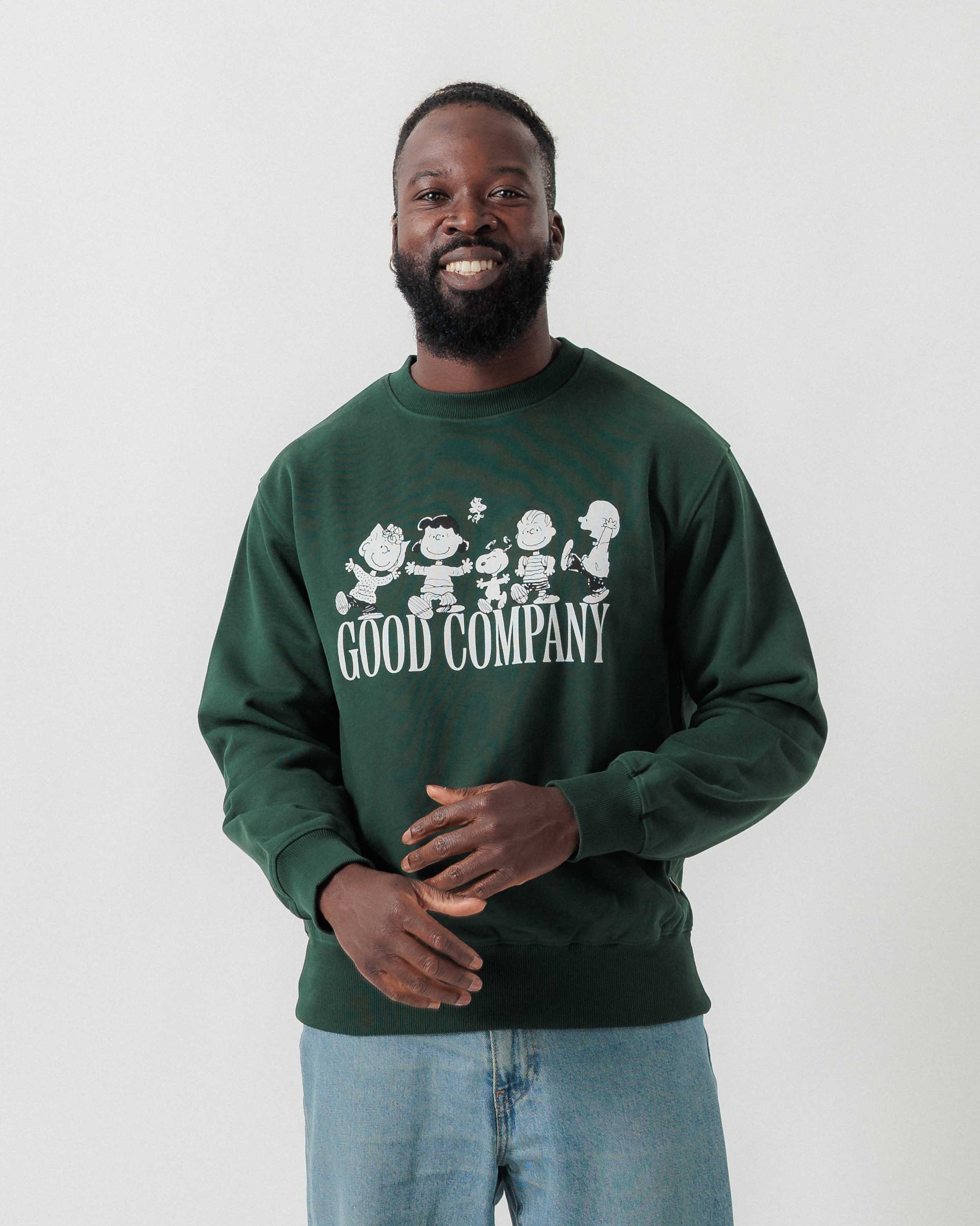 Vorderansicht eines männlichen Models im grünen Box Sweater mit Peanuts Good Company-Print.