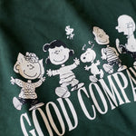 Detailaufnahme des Frontprints auf dem grünen Box Sweater. Snoopy und seine Freunde ausgelassen tanzend über dem „GOOD COMPANY“-Schriftzug.