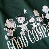 Detailaufnahme des Frontprints auf dem grünen Box Sweater. Snoopy und seine Freunde ausgelassen tanzend über dem „GOOD COMPANY“-Schriftzug.