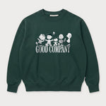 Vorderansicht des grünen Box Sweaters mit Peanuts Good Company-Print. Snoopy und seine Freunde ausgelassen tanzend über dem „GOOD COMPANY“-Schriftzug.