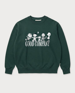 Vorderansicht des grünen Box Sweaters mit Peanuts Good Company-Print. Snoopy und seine Freunde ausgelassen tanzend über dem „GOOD COMPANY“-Schriftzug.