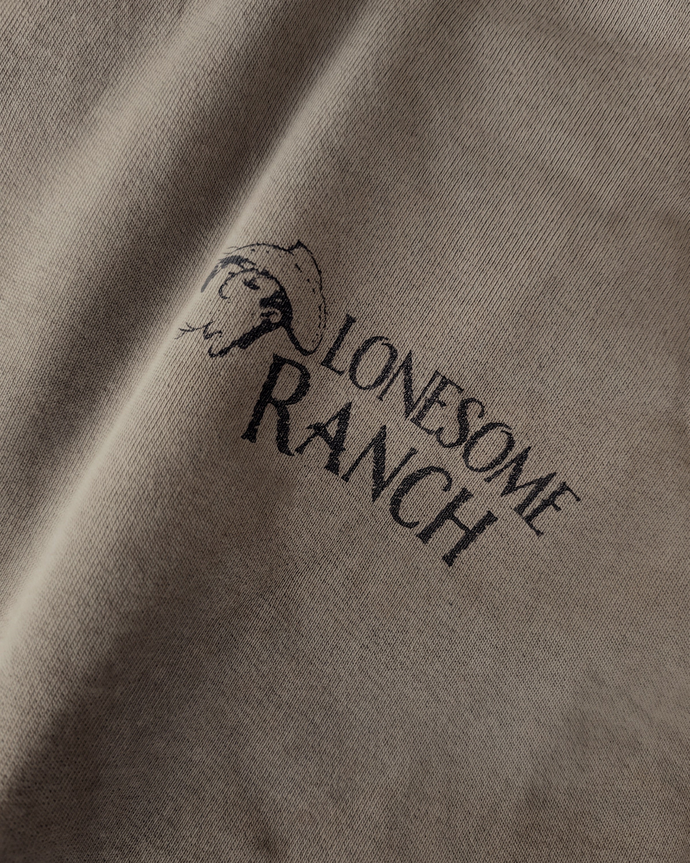 Detailaufnahme der Vorderseite des grauen Boxer Hoodies mit einem dezenten „Lonesome Ranch“-Print auf der Brust.