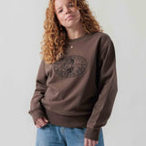 Vorderansicht eines weiblichen Models im braunen Box Sweater mit Lucky Luke Coffee Run-Stickerei.