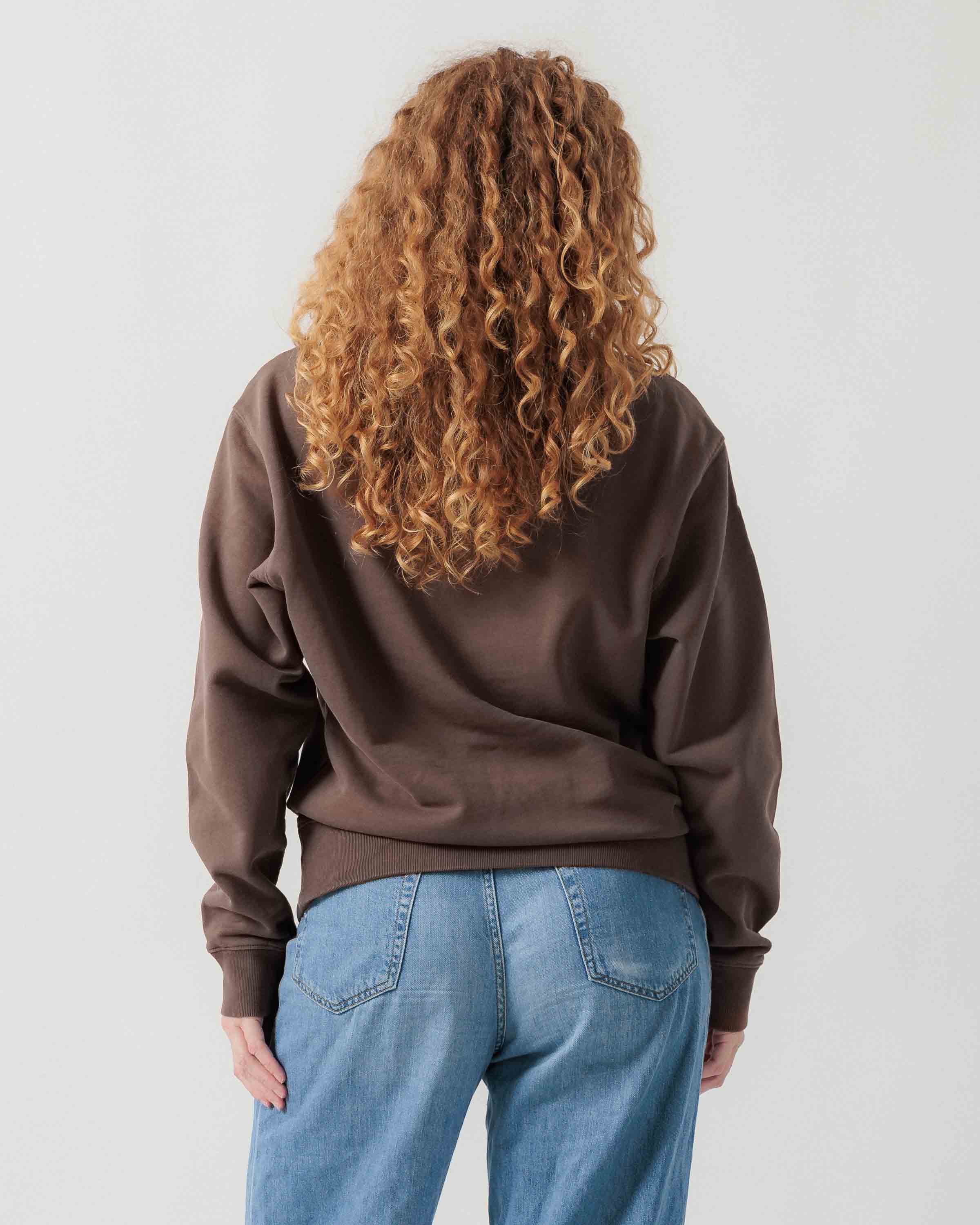 Rückansicht eines weiblichen Models im braunen Box Sweater.