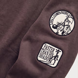 Detailaufnahme der Ärmel-Badges am braunen Boxer Hoodie.