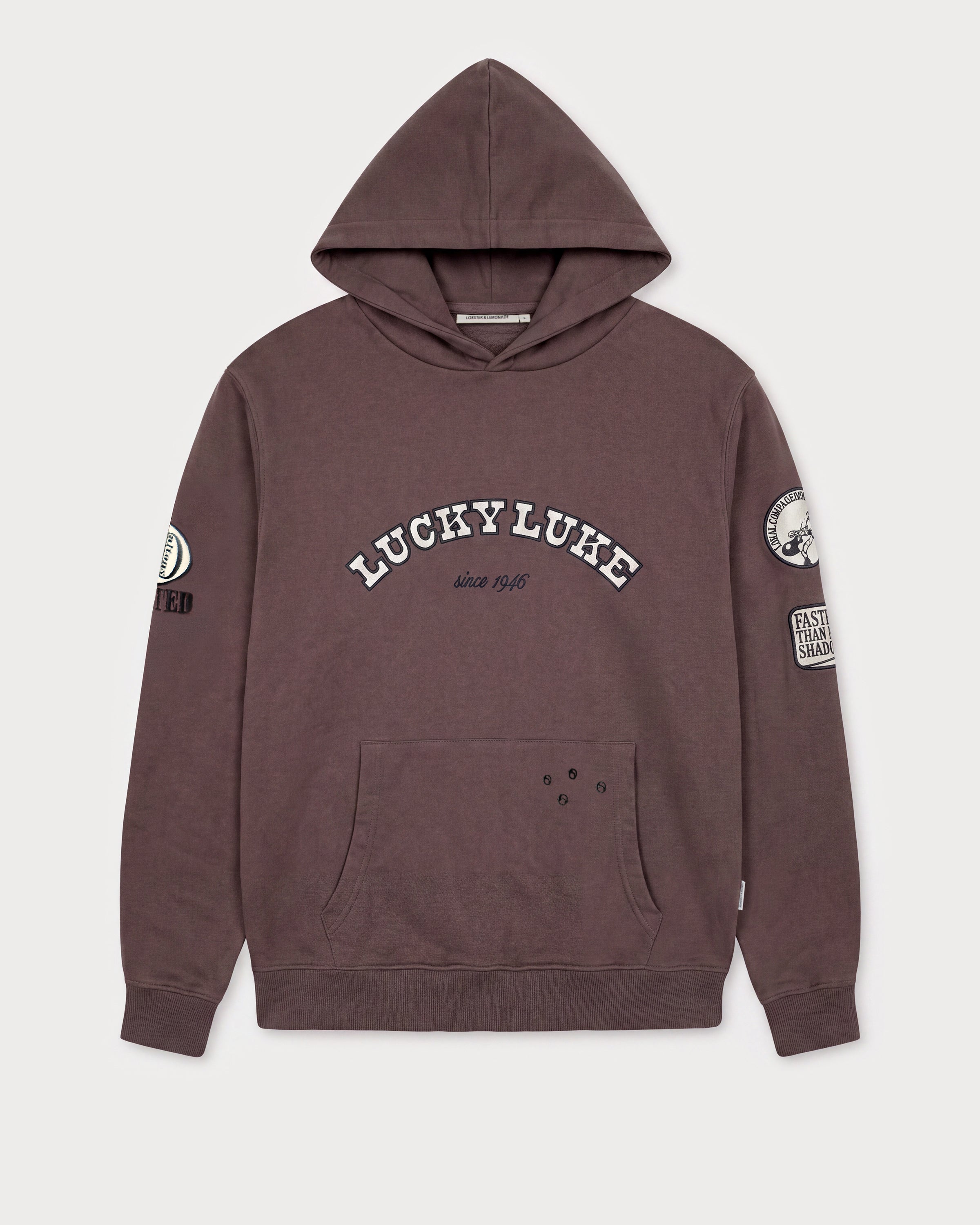 Vorderansicht des braunen Boxer Hoodies mit Lucky Luke Badges-Motiv. „LUCKY LUKE since 1946“-Schriftzug.