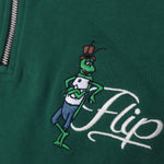 Detailaufnahme der Flip Script-Stickerei auf dem grünen Half Zip. Der lässige Flip, der sich an seinen eleganten Namensschriftzug lehnt.