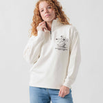 Vorderansicht eines weiblichen Models im weißen Half Zip mit Idéfix Happy-Stickerei.