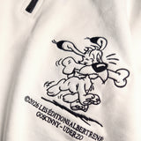 Detailaufnahme der Idéfix Happy-Stickerei auf dem weißen Half Zip. Der fröhliche Idefix mit einem Knochen.