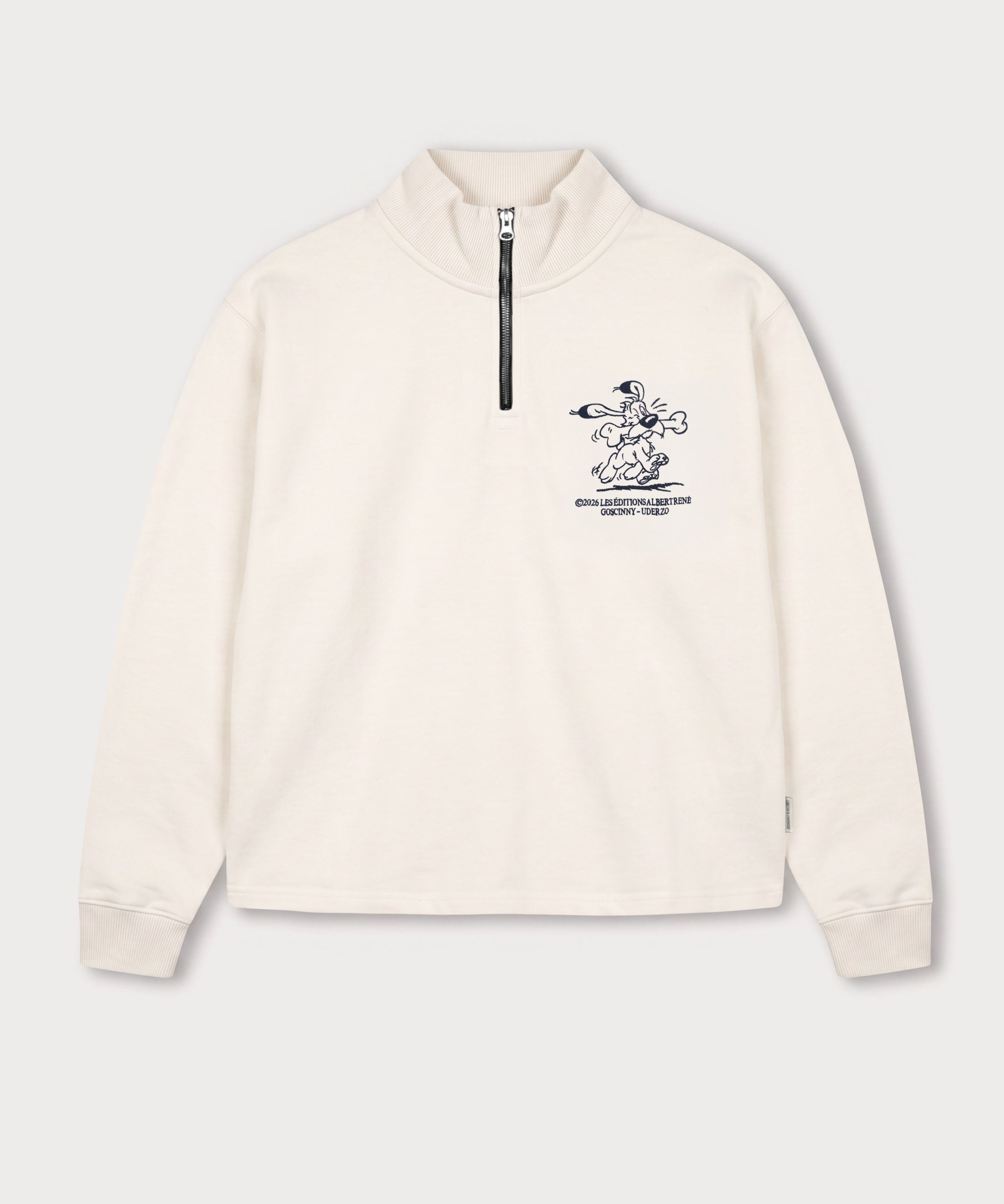Vorderansicht des weißen Half Zips mit Idéfix Happy-Stickerei auf der Brust. Der fröhliche Idefix mit einem Knochen.