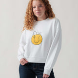 Vorderansicht eines weiblichen Models im weißen Sweater mit Snoopy Tennisball-Motiv.