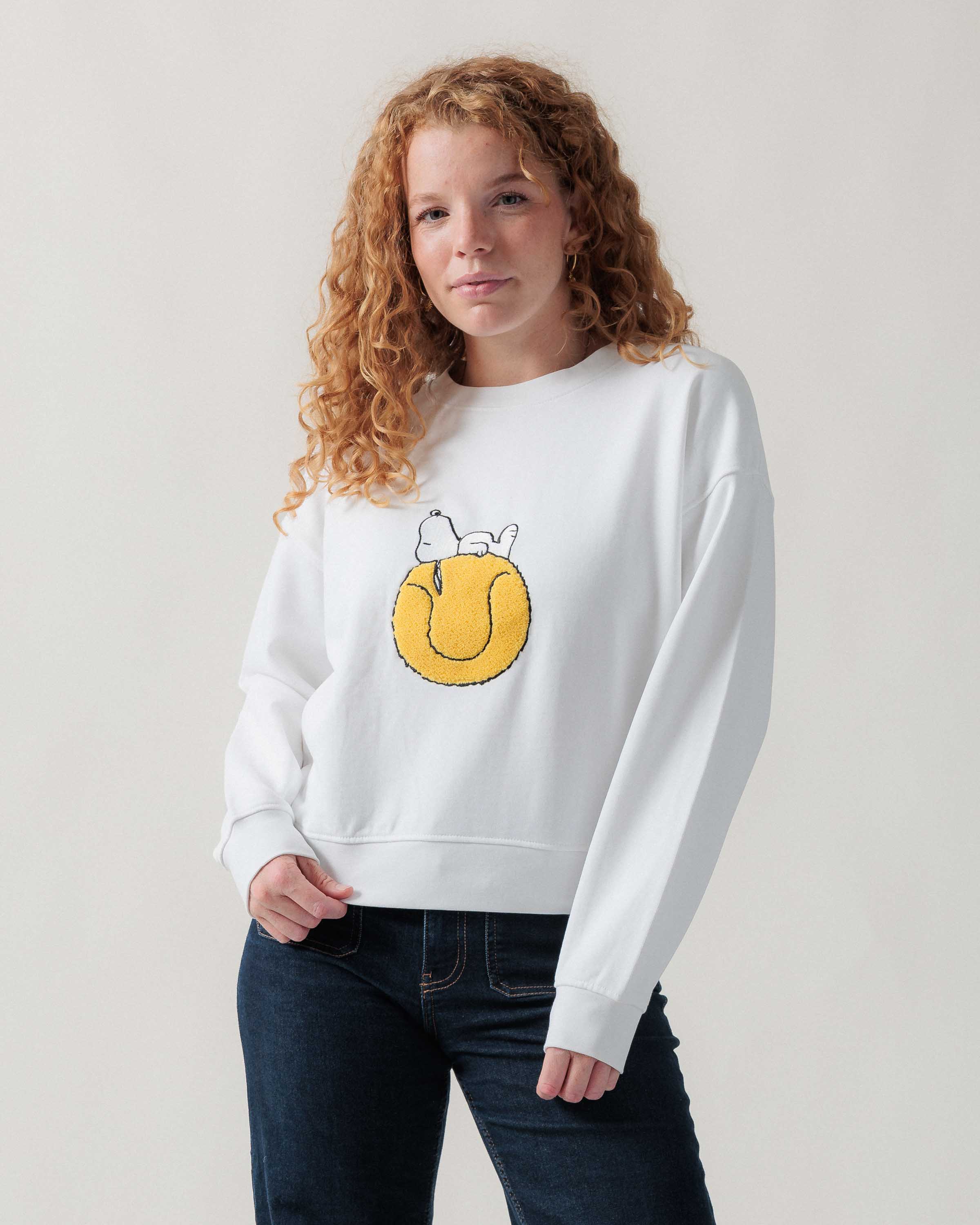 Vorderansicht eines weiblichen Models im weißen Sweater mit Snoopy Tennisball-Motiv.