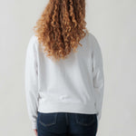 Rückansicht eines weiblichen Models im weißen Sweater.
