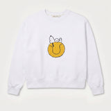 Vorderansicht des weißen Sweaters mit Snoopy Tennisball-Motiv. Tennisball, auf dem Snoopy tiefenentspannt relaxt.